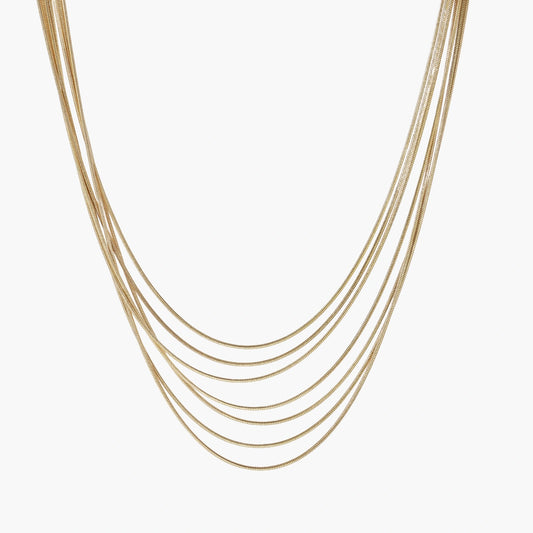 Seven delicate gold-plated snake chains create an elegant layered necklace on a neutral background.